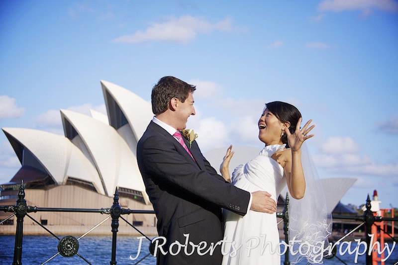Bride looking shocked at groom Dawes Point in front of opera house - wedding photography sydney